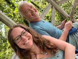 Lächelnde Frau und Mann sitzen entspannt auf einer Veranda in der Natur.