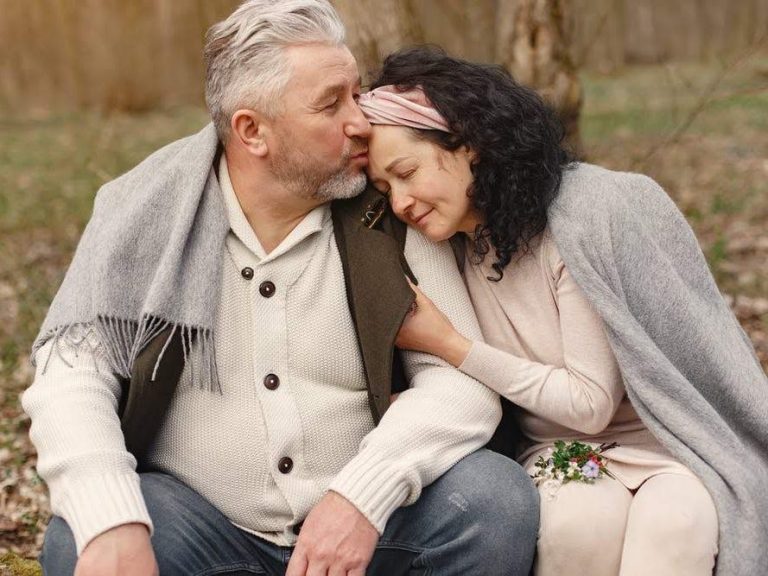 Ein älteres Paar sitzt zusammen im Freien und genießt einen liebevollen Moment.